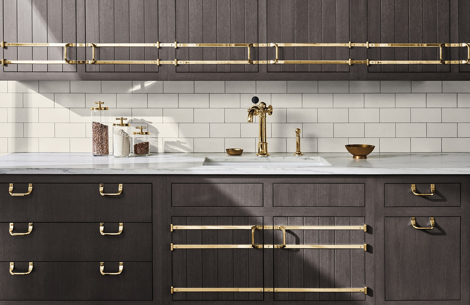 Dark oak kitchen cabinetry with polished brass rails and a brass faucet